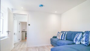 Un salón moderno con un sofá azul, paredes blancas y suelo de madera.