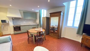 A modern kitchen with a dining area, a large mirror, and a TV.
