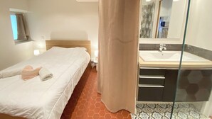 A hotel room with a bed, a bathroom with a sink and mirror, and a window with curtains.