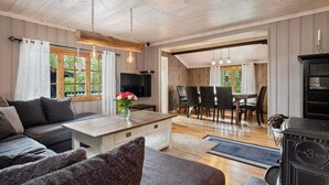 Een ruime woonkamer met een bank, een salontafel en een televisie. Er is een eethoek met een tafel en stoelen.