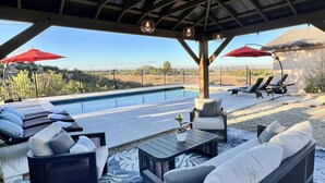A poolside area with lounge chairs, a covered seating area, and a view of a pool and landscape. - Large Cozy Estate w/ VIEWS! 5 Min to Downtown (Paso Robles)