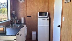 A compact kitchen with a sink, toaster, kettle, and a microwave on a white refrigerator.