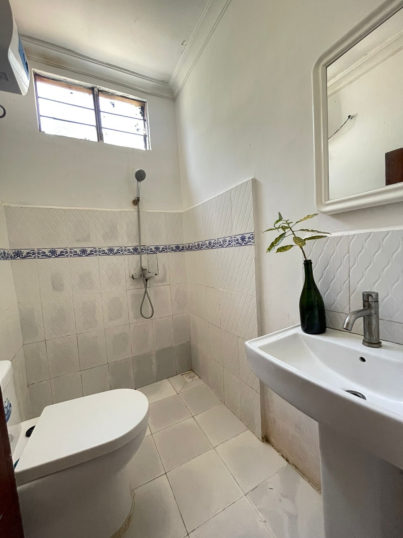 Baño con inodoro, lavamanos, ducha y ventana.