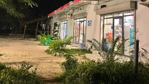 Een gebouw met een rood dak en meerdere ramen, omgeven door groen en een grindpad.