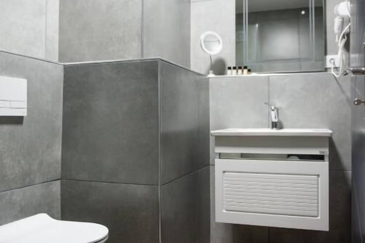 Un baño moderno con inodoro independiente, tocador con espejo y zona de ducha.