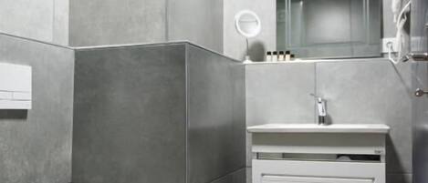 A modern bathroom with a freestanding toilet, a vanity with a mirror, and a shower area.
