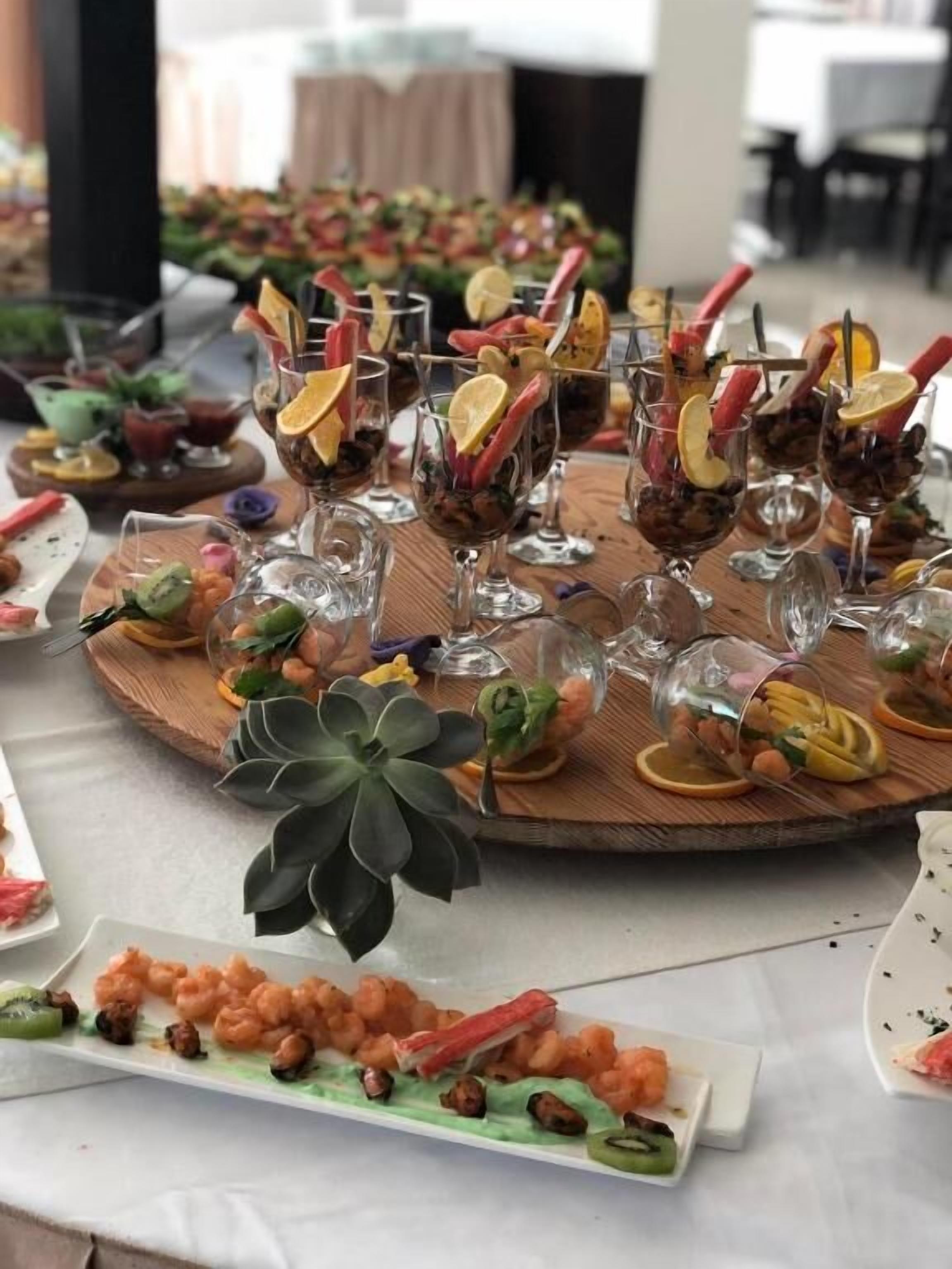 Een tafel gedekt met verschillende soorten eten en drinken, waaronder garnalen, fruit en drankjes in glazen.