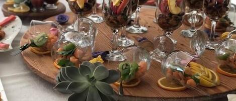 Een tafel gedekt met verschillende soorten eten en drinken, waaronder garnalen, fruit en drankjes in glazen.