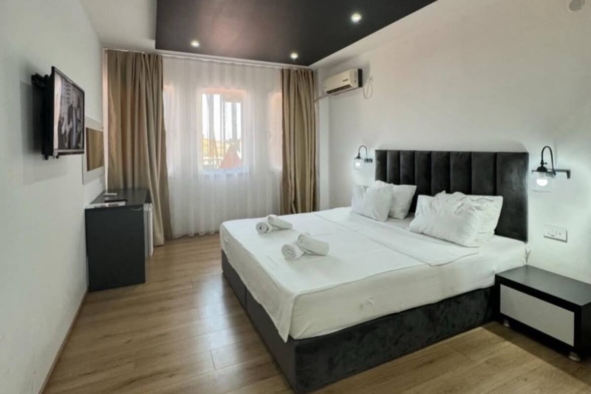 Un dormitorio moderno con una cama grande, una mesita de noche y un ventanal con cortinas.