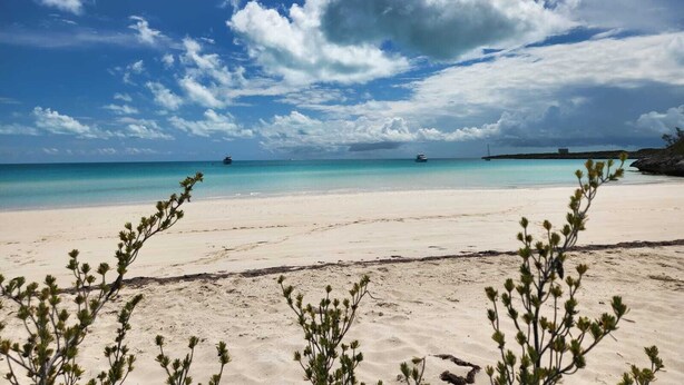 A beach with clear turquoise water, a boat in the distance, and a large cloud in the sky. - New 3-bed oceanview villa, Black Point, Exuma near Staniel, AC, Wifi dock access (Black Point Exuma)