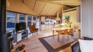 Uma sala de estar moderna com televisão, assentos e área de jantar.