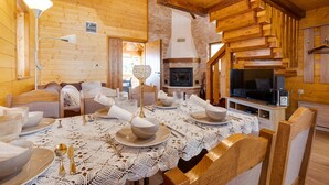Une chaleureuse cabane en bois comprenant un coin repas aménagé pour quatre personnes, une cheminée et un téléviseur.