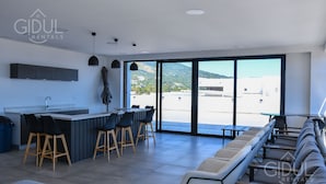 A modern kitchen with a bar area, large sliding glass doors to a balcony, and a seating area with a sofa and chairs.
