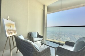 A modern room with a large window, wicker furniture, and an easel with a painting. - Exclusive High-Floor 2BR Aykon with Luxury & Views (Dubai)