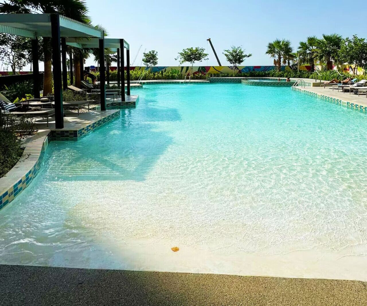 Une piscine aux eaux cristallines, dotée de chaises longues et d’un espace abrité.