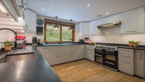 A modern kitchen with a large island, stainless steel appliances, and a view of the outdoors. - Chalet Chavanette - spacious holiday home for 12 with spa - OVO Network (La Chapelle-d'Abondance)