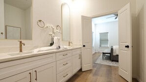 Une salle de bain moderne avec un grand miroir, des meubles blancs et un plancher en bois.