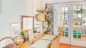 Una habitación acogedora con una mesa de madera, obras de arte enmarcadas, una cesta y una estantería con objetos decorativos.