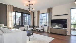 Un salon moderne avec un canapé, des fauteuils, une table basse, une cheminée et de grandes fenêtres.