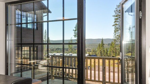 Une pièce dotée de grandes fenêtres donnant sur une terrasse et la forêt environnante.