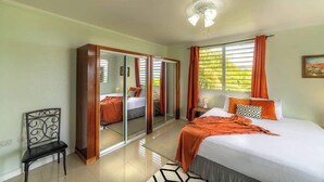 Un dormitorio con cama, una silla, un armario y un ventilador de techo.