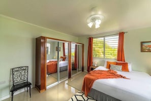 A bedroom with a bed, a chair, a wardrobe, and a ceiling fan.