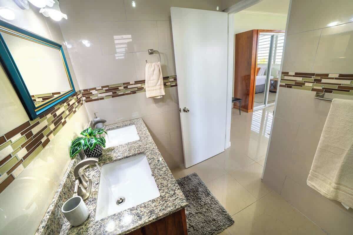 Un baño con dos lavamanos, un espejo y un perchero para toallas.