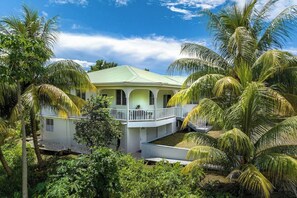 Un edificio de dos pisos con techo verde, rodeado de palmeras.