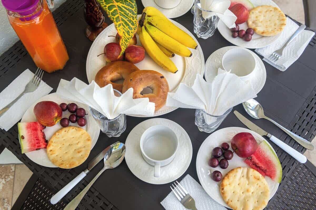 Een gedekte tafel met borden eten, inclusief fruit, brood en een kop thee.