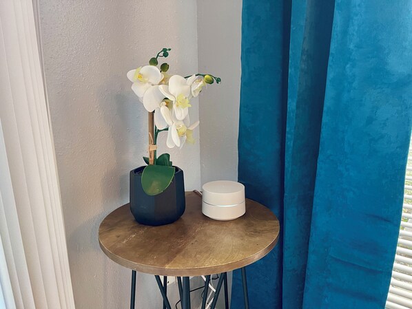 Una mesa redonda pequeña con una orquídea en maceta y un recipiente blanco.