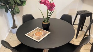 A round table with a magazine, a potted plant, and two chairs.