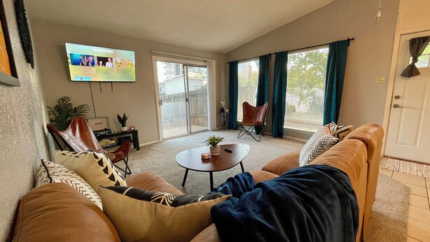 A living room with a sofa, a coffee table, and a TV mounted on the wall.