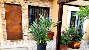 A house entrance with a stone wall, a wooden door, and potted plants. - Villetta Alessandra Ostia Antica 10 mins from beach (Lazio)