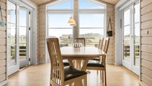 Un espace repas avec une grande table, des chaises en bois et un luminaire suspendu.