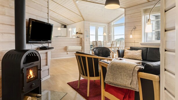 Un intérieur de chalet chaleureux avec un poêle à bois, une télévision, un coin repas et un canapé.