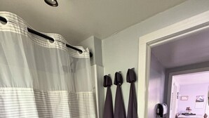 Un baño con cortina de ducha, toallero con toallas, lavabo y alfombra.