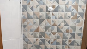 Un baño con inodoro, bidé y una pared con patrones geométricos de azulejos.