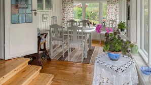 A cozy dining area with a wooden table and chairs, a lace table runner, and a potted plant on a windowsill.