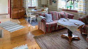 A cozy living room with a striped sofa, a dining table with chairs, and a wooden cabinet.