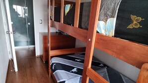 A bunk bed with a wooden frame and a black and white patterned mattress. There is a wooden wardrobe to the left and a door leading to another room. - Cozy apartment (Pueblo libre)