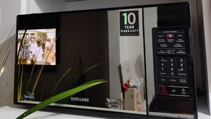 A Samsung microwave with a 10-year warranty, a digital display, and a control panel with various cooking options. - Cozy apartment (Pueblo libre)