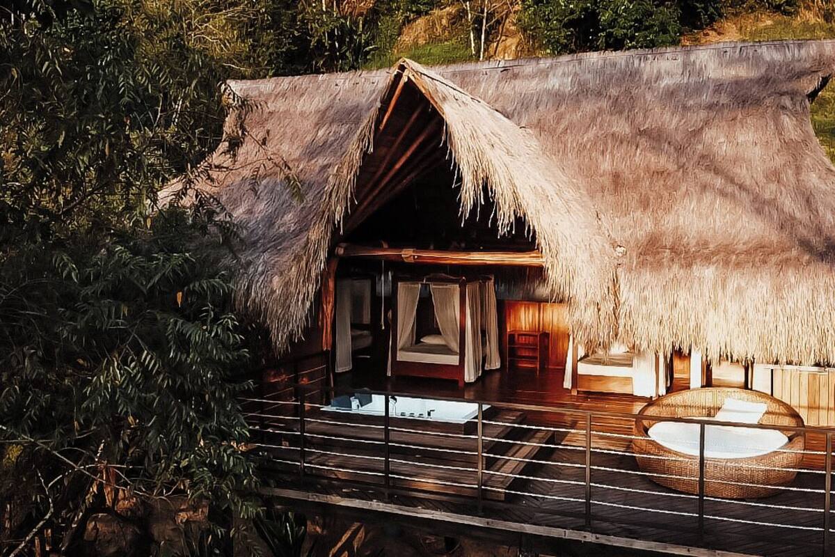 A thatched-roof structure with a wooden deck and a circular seating area.