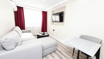 Suite familiar, 1 cama King size y sofá cama, balcón, vista a la ciudad | Sala de estar | Smart TV de 55 pulgadas con canales digitales y libros