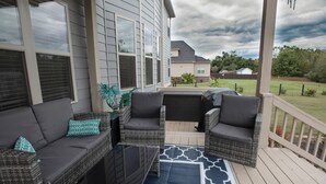 Un espacio de estar al aire libre cubierto con muebles de mimbre y un tapete azul estampado.