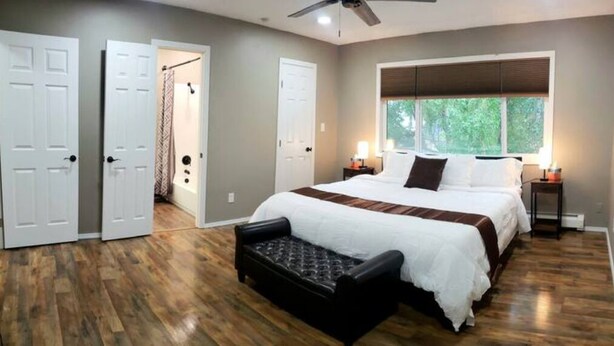 Un dormitorio con una cama grande, un banco y una ventana con persianas.
