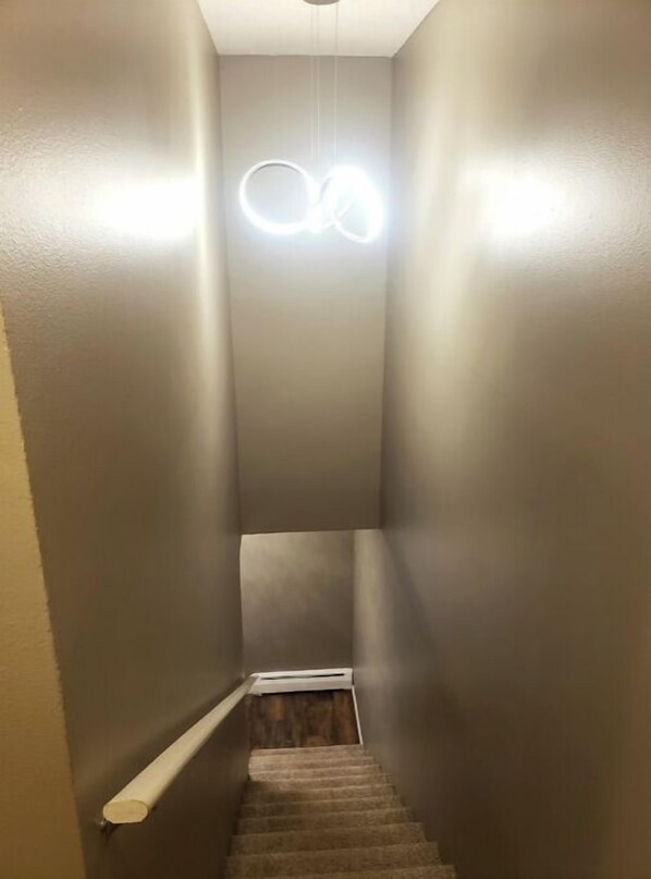 Una stretta scala con un moderno apparecchio di illuminazione in cima.