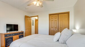 Een slaapkamer met een groot bed, een houten garderobe en een televisie op een dressoir.