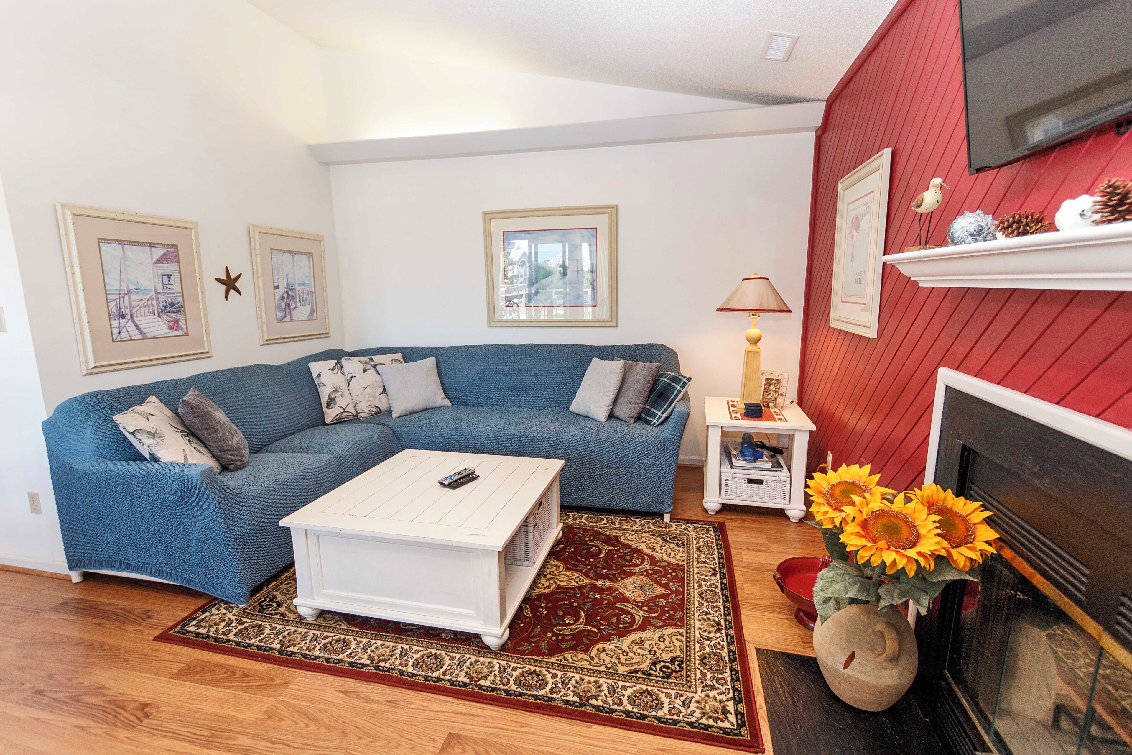A living room with a blue sofa, white coffee table, and a fireplace.