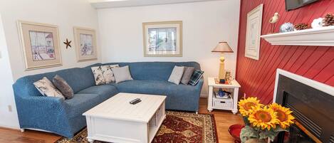 A living room with a blue sofa, white coffee table, and a fireplace.