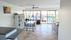 A spacious kitchen with a dining area, large windows, and a view of the city. - Burleigh Breeze Coastal (Burleigh Heads)